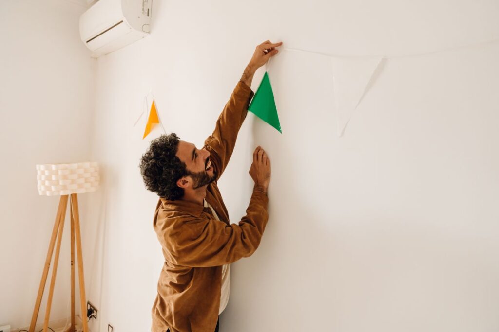 Ein Mann befestigt eine Wimpelkette an der Wand zur Vorbereitung auf eine Feier – perfekter Anlass, um Stuehle zu mieten statt selbst zu schleppen.